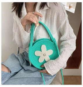 Gros plan du sac à bandoulière rond en tricot vert avec fleur blanche et perle