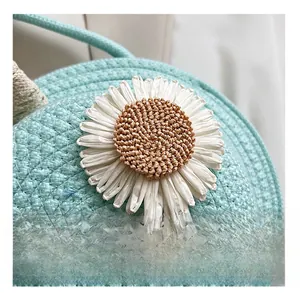 Close-up of woven straw texture with a decorative white daisy flower on a blue crossbody bag