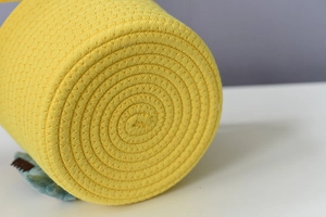 Detailed close-up of yellow cotton rope woven storage basket with soft plush accent