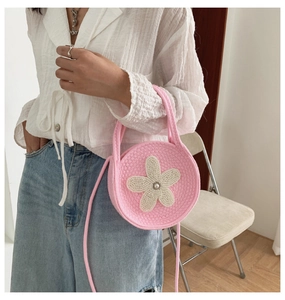 Détail du sac à main rond en tricot rose avec fleur blanche et perle décorative