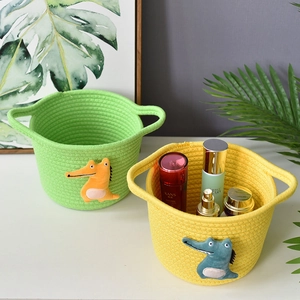 Close-up of yellow and green cotton rope storage baskets with cartoon crocodile patches
