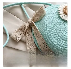 Close-up of light blue round woven straw bag with white daisy and beige lace bow detail