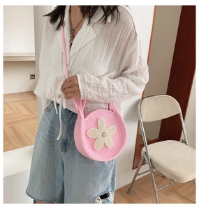 Détail du sac rond tissé rose avec des décorations de fleurs en perles blanches élégantes