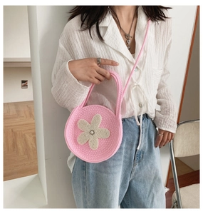Détail du sac à bandoulière rose tricoté avec fleur blanche au crochet et perle