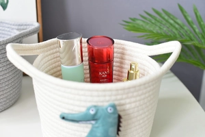 Detail view of woven cotton rope basket featuring cute crocodile decor and wide handles