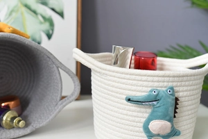Detail of hand-woven cotton rope storage basket with cute green crocodile patch
