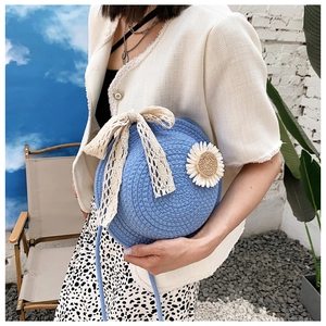 Detail of round sky blue straw crossbody bag with lace bow and floral applique