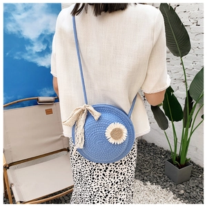 Detailed shot of sky blue round woven straw crossbody bag with sunflower decoration