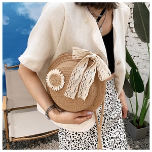 Detail of round straw bag with white lace bow and daisy decor in outdoor setting
