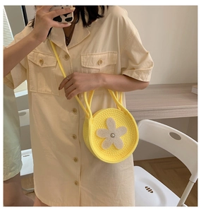 Détail d'un sac à main rond jaune en maille avec fleur de perles porté par un mannequin