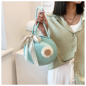 Detail of mint green straw round bag with daisy flower patterns and lace bow