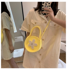 Détail d'un sac à bandoulière en tricot jaune vif avec une grande fleur en perle