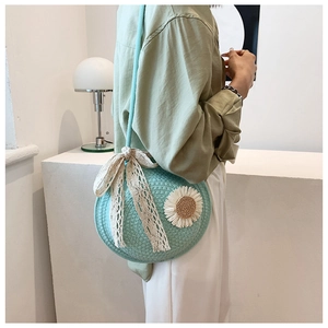 Detail of round straw crossbody bag in mint green with daisy flower and lace bow