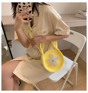 Détail du sac à main rond tissé jaune vif avec une fleur en perles blanches