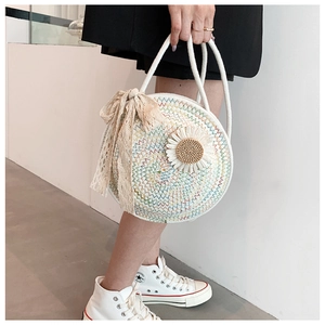 Close-up of circular straw bag with daisy flower decor and lace ribbon handle