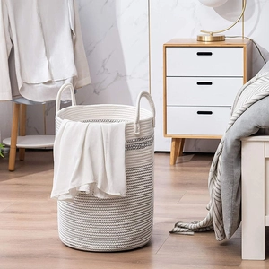 Close-up of a white woven cotton rope storage basket with grey stripes in a cozy bedroom