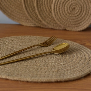 Detailed close-up of natural jute woven round placemat with textured spiral pattern on wood