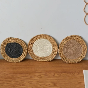 Macro detail of three braided round placemats showing natural grass fiber texture