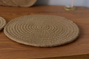 Close-up of circular braided jute placemat with natural heat-resistant fiber texture