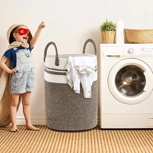 Detail of a large cotton rope woven laundry basket with handles in a laundry room