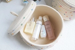 Detail of Nordic woven cotton rope storage basket with lid and colorful pom-poms
