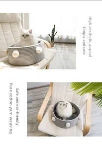 Detail of round light grey cotton rope pet bed with white pompoms in home setting