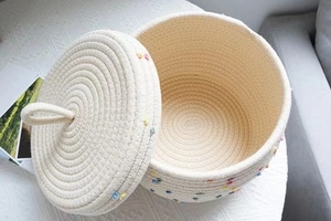 Macro shot of Nordic cotton rope storage basket with lid and colorful pompom details