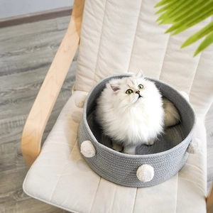 Grey woven cotton rope cat bed with white pom-poms and cozy interior for small pets