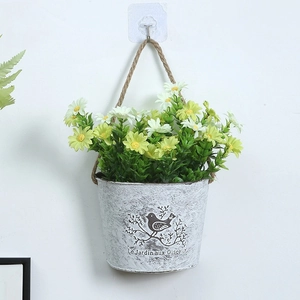 Macro view of artificial daisies in vintage white metal pot with jute rope hanger