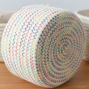 Detail of multi-color rainbow stitching on woven white cotton rope storage basket
