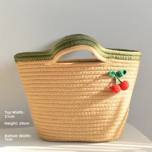 Detailed view of handmade woven tote bag with 3D red cherry accents and olive green handles
