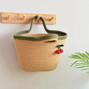 Close-up of cotton rope woven tote bag with crochet cherry charms on a wooden wall hook