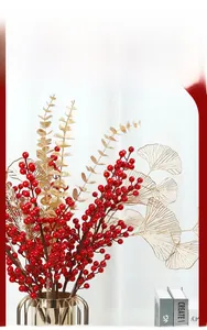 Detail view of festive red holly berries with golden eucalyptus leaves in a glass vase