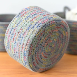 Close-up of a woven cotton rope basket featuring colorful rainbow zigzag stitching detail