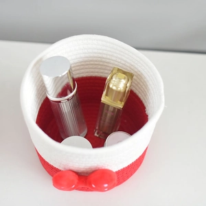 Close-up of a woven cotton storage basket with a red bow showing skincare products inside