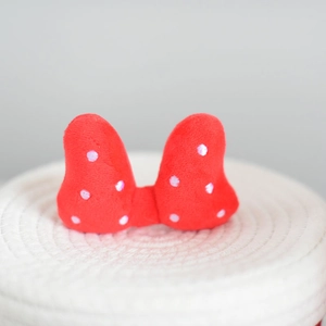 Close-up of a red plush bow with white polka dots on a woven storage basket lid