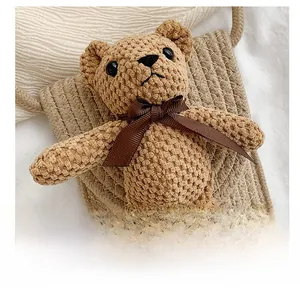 Close-up of beige woven straw bag featuring a cute brown plush bear with a silk bow