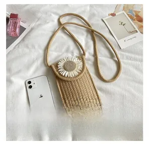 Detailed macro view of woven crossbody phone bag with floral daisy decor on white fabric