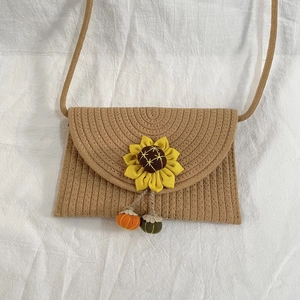 Detail of hand-woven straw crossbody bag with sunflower accent and pumpkin charms