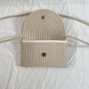 Detail view of the beige woven shoulder bag featuring a magnetic gold clasp closure