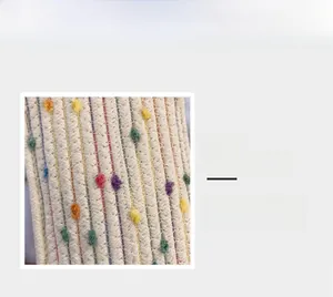 Macro detail of straw woven mini bag showing colorful pom-poms and texture