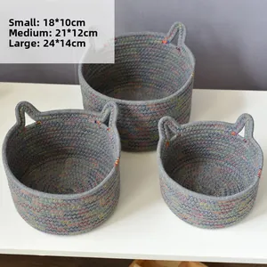 Detailed set of three grey woven cotton baskets with cat ear handles in varied sizes