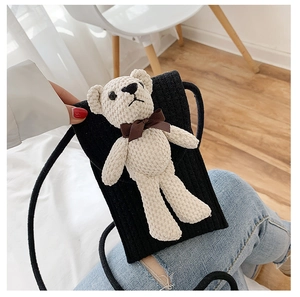 Close-up of cute knitted teddy bear decoration on black corduroy mini crossbody bag