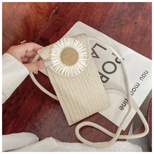 Close-up of a beige woven phone bag with a large white daisy flower and gold bead detail