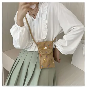 Detail view of woven straw mini bag featuring colorful embroidery and large pearl buckle