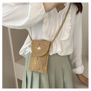 Detail view of mini straw crossbody phone bag with pearl clasp and colorful polka dots