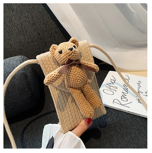 Detail of hand-woven straw crossbody phone bag featuring a cute 3D crochet bear charm
