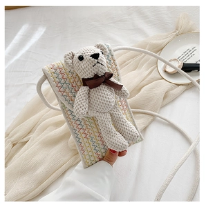 Close-up of woven straw phone bag with a 3D teddy bear and colorful zigzag pattern