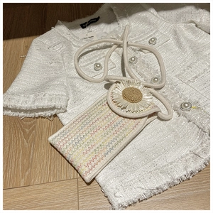 Close-up of woven daisy bag with rainbow texture on white tweed background