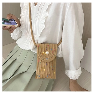 Detail of bohemian straw phone bag with colorful dots and large faux pearl closure